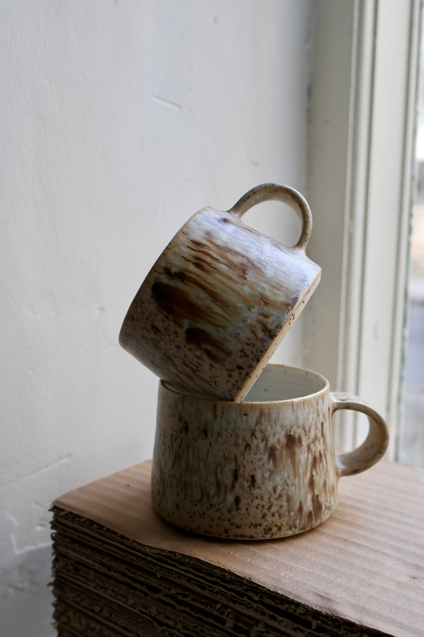 Hand-thrown medium tapered cup in speckled stoneware, featuring a matte white interior and smooth matte birch exterior glaze. Crafted by Ela Grima in Malmö