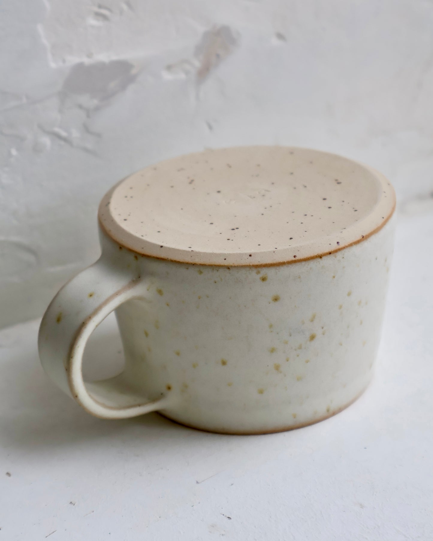 Side view of stoneware cup with matte white finish.