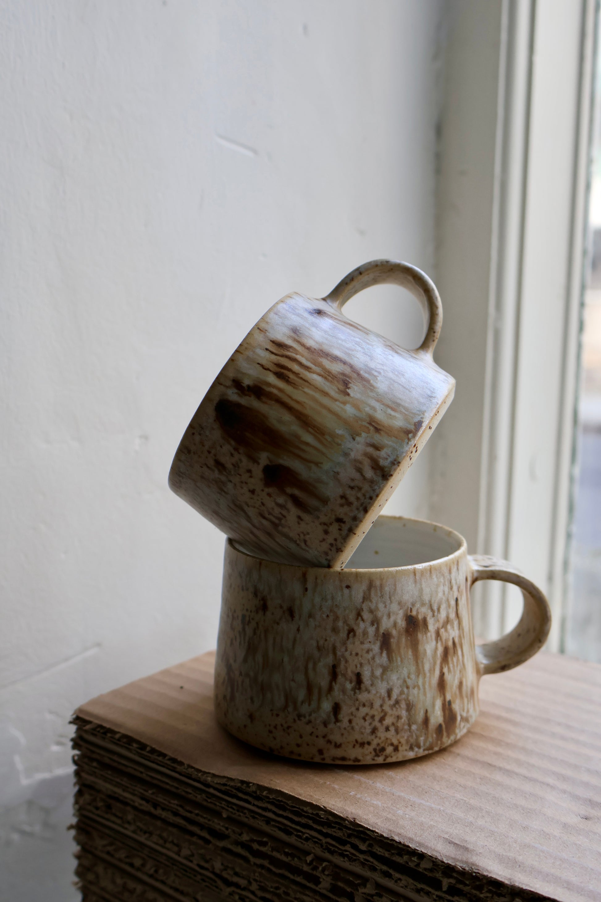 Hand-thrown medium tapered cup in speckled stoneware, featuring a matte white interior and smooth matte birch exterior glaze. Crafted by Ela Grima in Malmö