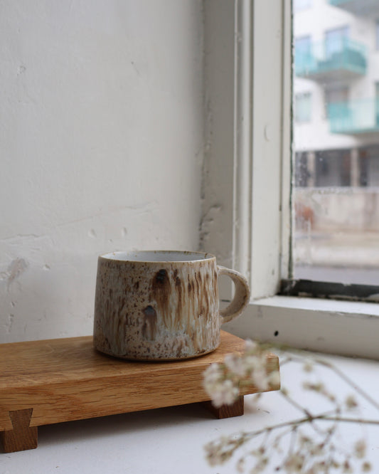 Hand-thrown medium tapered cup in speckled stoneware, featuring a matte white interior and smooth matte birch exterior glaze. Crafted by Ela Grima in Malmö