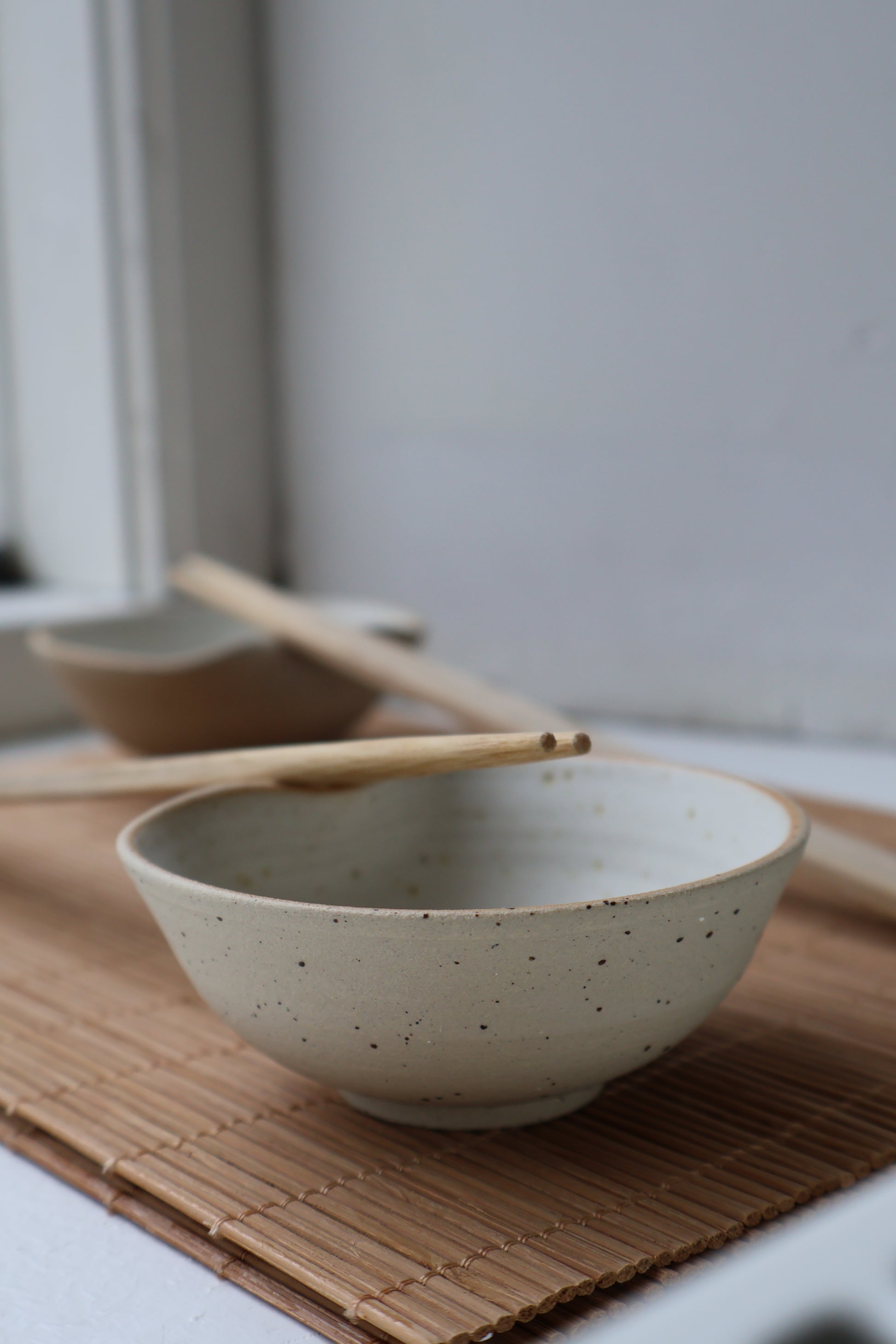 Stoneware sushi bowl featuring raw speckled clay exterior and chopstick rest