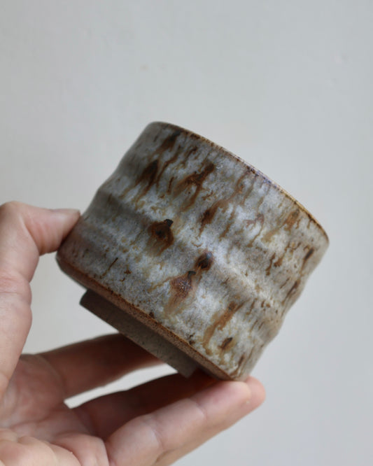 Hand-thrown organic stoneware tumbler in a speckled ash glaze, shown against a white background.